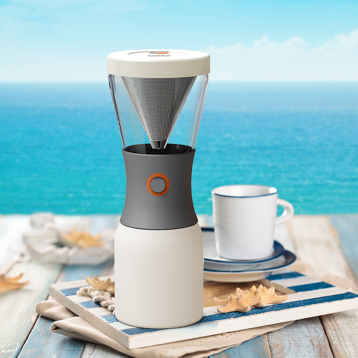 Cup of coffee on wooden table with blue sea in background.